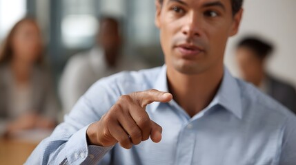 Obraz premium A man in a business meeting points forward assertively while speaking with colleagues blurred in the background