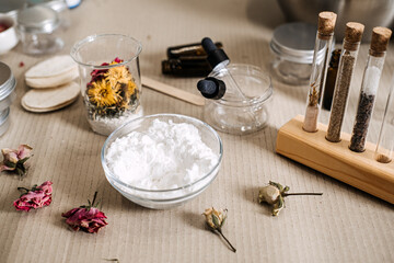 Composition of white powder, test tubes, and dried flowers on textured surface. sensory beauty, ingredient textures, colorful apothecary, aesthetic raw materials.