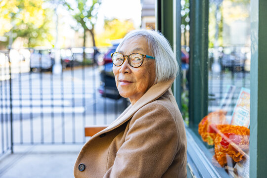Portrait of Senior Asian Woman sitting outside a storefront