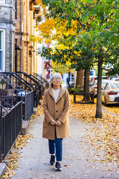 Senior asian woman walking down a city street in autumn