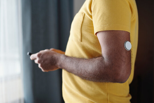 Person with insulin patch monitoring diabetes indoors using device