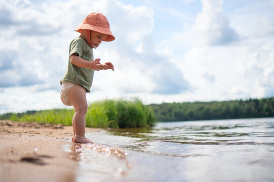 A child runs on the sandy beach with an orange hat, embodying the energy and excitement of outdoor fun.