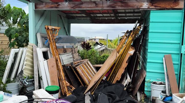 Wind moves stored boards and equipment inside an open makeshift shelter