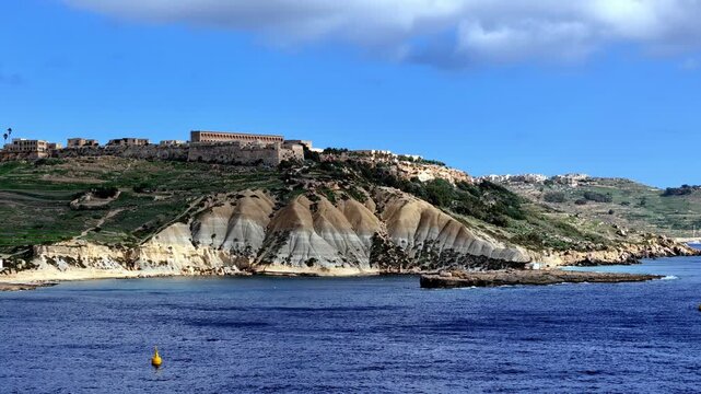 Scenic Coastal View of Fort Chambray and Blue Clay Cliffs Overlooking Mediterranean Sea During Sunny Day in Ghajnsielem Gozo Malta with Deep Blue Water Horizon and Low Angle Perspective from drone