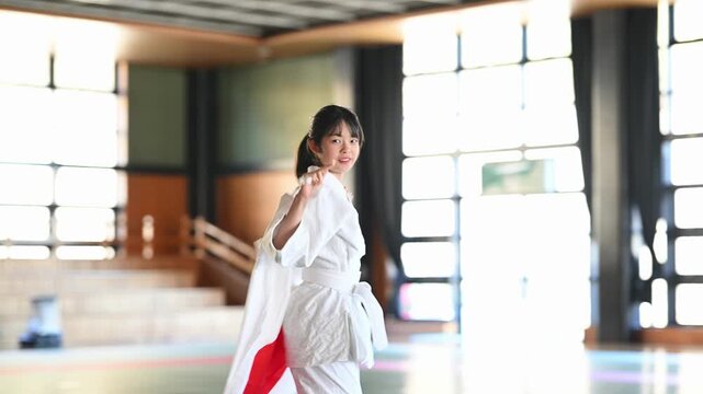 日の丸を掲げて走る空手着の小学生の女の子　スポーツの応援と勝利のイメージ