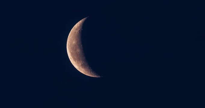 Timelapse of a waxing crescent Moon moving across a dark night sky. Detailed lunar surface with visible craters and terminator line, illustrating the lunar phase cycle and astronomical motion.