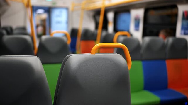 Commuter train interior with colorful seating and yellow grab handles