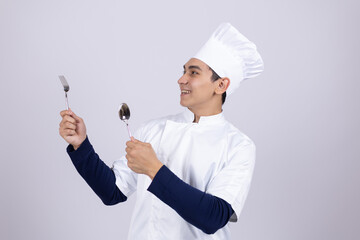 Young chef holding kitchen utensils and tasting food