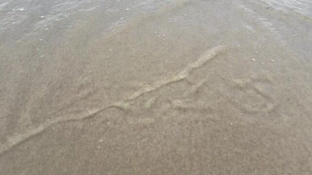 2025 text on smooth sand near waterline before waves reach it. Quiet coastal symbolism. Concept of goodbye reset fresh start planning and annual review for business and personal transformation content