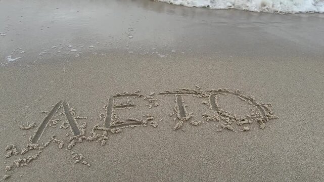 Russian word leto meaning summer written on sand near waterline and slowly erased by waves. Seasonal goodbye concept. Useful for travel brands summer campaigns and Russian language audiences.