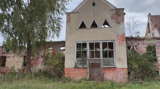 Old abandoned brick building with damaged facade standing in rural landscape. Historic architecture from past century represents concept of decay, forgotten places, lost history, passage of time and