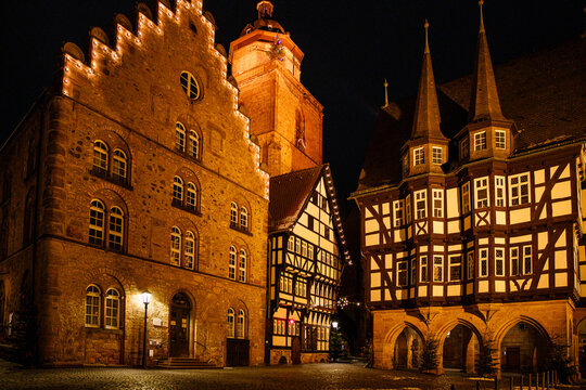Snow-covered market square in Alsfeld, Hesse, with historic half-timbered houses, city hall and a decorated Christmas tree in a quiet winter atmosphere by night.