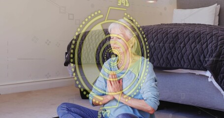 Naklejka premium Sitting senior wearing blue shirt, jeans praying at chest on dark mat beside bed, yellow HUD