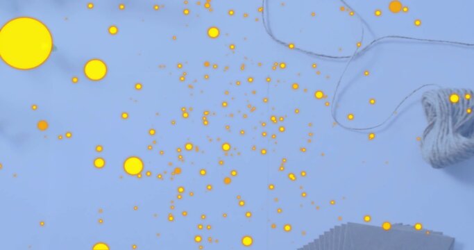 Scattering bright yellow dots covering pale blue tabletop, with ball of twine and stacked paper