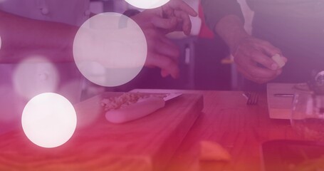 Chopping chefs' hands with white jacket sleeves slicing garlic in kitchen on cutting board, knife