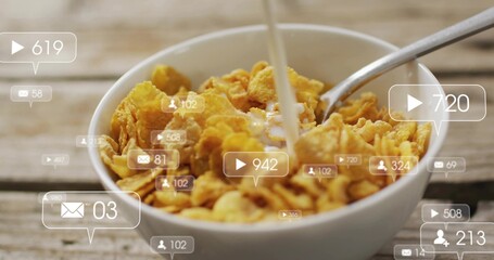 Pouring milk into white bowl of cornflakes on worn wooden table, spoon, social overlays floating © vectorfusionart