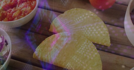 Showing two yellow tacos on wooden slats, bowls with salsa, salad, pale dip and purple reflections © vectorfusionart