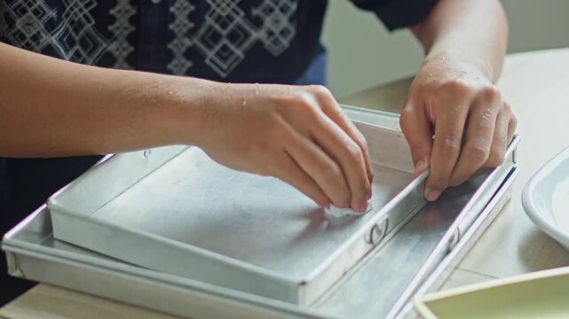 Someone meticulously greasing edges of metal cake tin in preparation for baking
