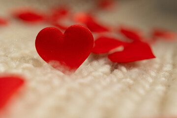 Fototapeta premium Red fabric hearts are scattered across a soft, textured surface, creating a romantic atmosphere perfect for Valentine's Day inspired digital content.