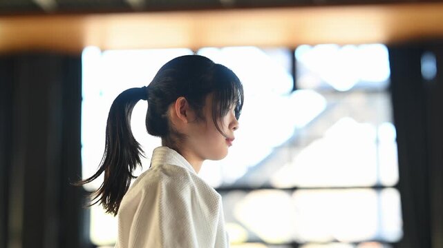 道場で気合の掛け声を出す空手着の女の子の横顔