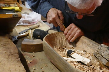 Senior man carving wood bowl with chisel