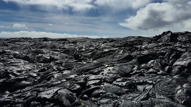 Panning view across vast dry lava flows under sunlight in Hawaii