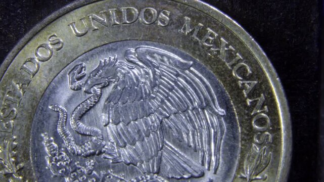 Macro closeup of a Mexican bimetallic coin showing the eagle and snake national emblem with raised lettering, metallic texture, and reflective highlights.