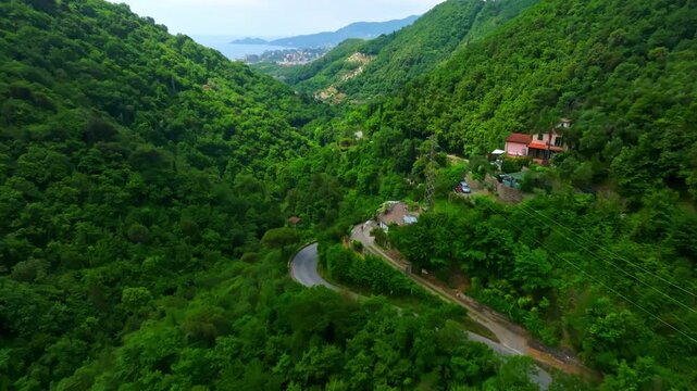 Drone flyover homes and a mountain road, toward Rapallo, summer day in Italy