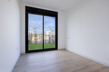 Obraz premium Empty modern bedroom with wood flooring and large glass door to private garden