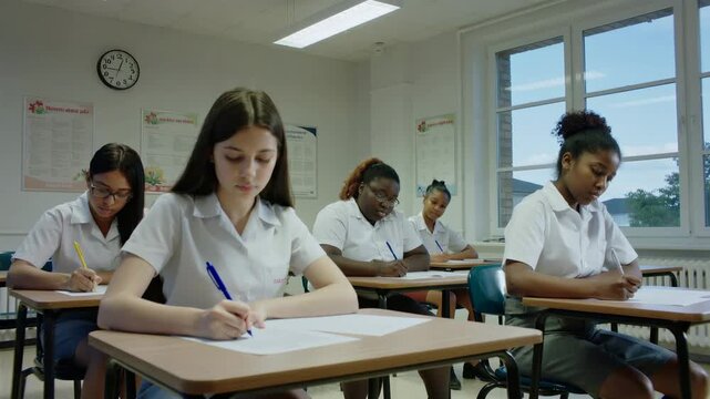 Students focused on writing an exam in a bright classroom setting