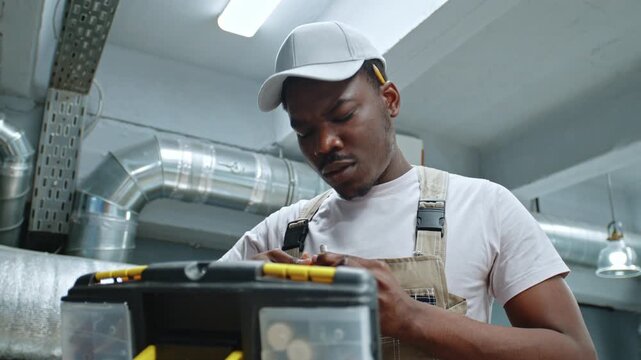 Man works in workshop and organizes tools in toolbox while preparing for project