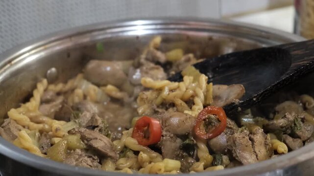 Creamy rotini Fusilli Macaroni and chicken liver with fried celery, vegetables. Preparation in stewpan, with savory sauce. Commercial kitchen
