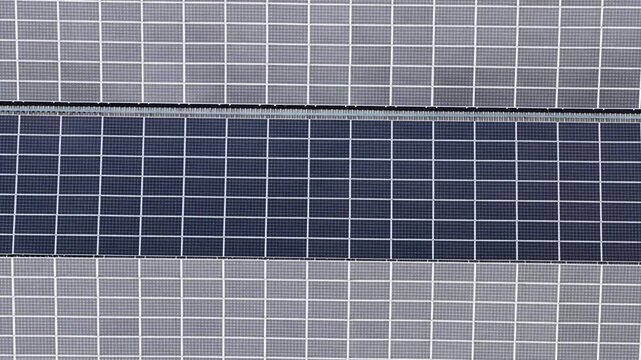 Aerial view of solar panels arrayed in neat rows, creating an abstract pattern of light and dark rectangles, Trieste, Friuli-Venezia Giulia, Italy.