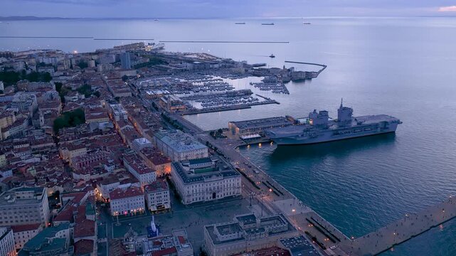 Aerial view of Trieste's harbor, where a large ship docks near the city; the scene shows the quiet beauty of the city at dusk, Trieste, Friuli-Venezia Giulia, Italy.