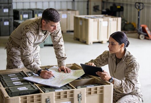 Military personnel planning logistics strategy with map and tablet