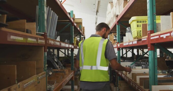 Male warehouse worker entering aisle, checking stock on tablet, picking parts, AR UI marking stock
