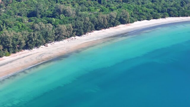 Aerial drone view of Koh Phayam coastline showing turquoise waters, sandy beach, and dense tropical forest under calm daylight conditions.