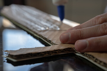 Close-up of hands working on a cardboard prototype at a desk. Startup project concept, product development, prototyping process, creativity, and innovation. Hands-on work, no face visible.
