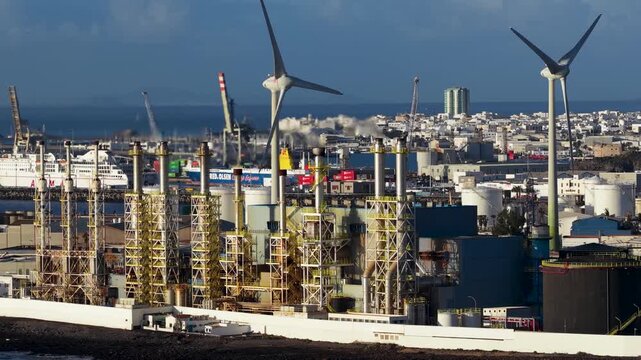 Aerial view of the industrial Punta Grande Power Station with its towering wind turbines amidst the urban landscape, Teguise, Lanzarote, Canary Islands.