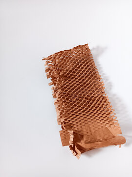 Close up of a piece of brown honeycomb packing paper isolated on white background. An eco-friendly alternative for wrapping fragile items, protective packaging material during shipping.