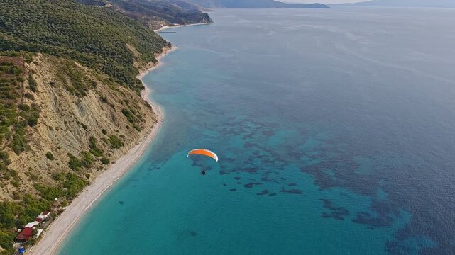 Aerial panorama of paragliding above blue sea and sandy beaches along the Albanian coast, capturing coastal landscape, tourism, and outdoor sport activities