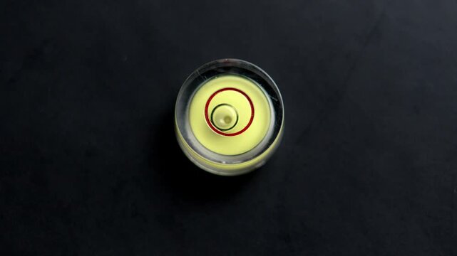 Circular spirit level on black background. Precision alignment instrument for engineering and calibration control