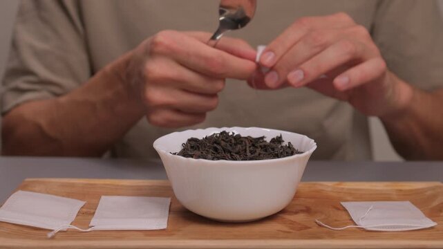 Artisan tea bag filling process, Careful and detailed artisanal approach to tea packaging, Meticulous handpicked tea bags with loose leaves and scattered empty sachets on tray