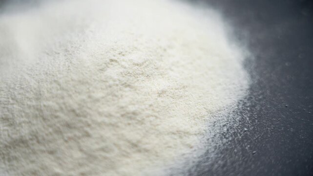 Whey protein powder on a black ceramic plate. Fitness nutrition concept. Rotation