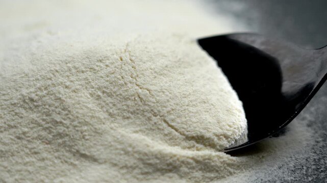 Metal spoon scooping a portion of fine collagen protein mix from a pile on a black background. Nutritional concentrate. Healthy lifestyle and recovery concept