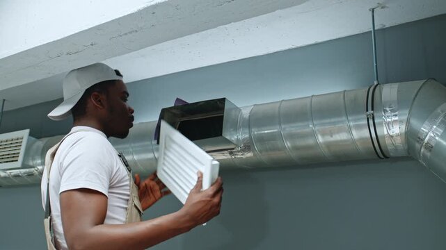 Worker inspects duct system in indoor space to maintain air quality and efficiency