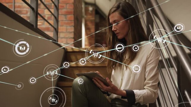 Woman on stairs tapping tablet and generating shopping cart and chart nodes, mapping commerce web