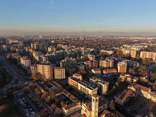 A sprawling cityscape unfolds beneath a clear, blue sky, showcasing a blend of residential buildings, and open spaces, offering a glimpse into the rhythm of urban life.
