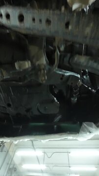 Full Chassis Undercoating Application Showing Floor Pan And Suspension Mounts. Black Protective Layer Covers Frame Rails And Cavities, HighCoverage Finish With Visible Brush And Spray Patterns,
