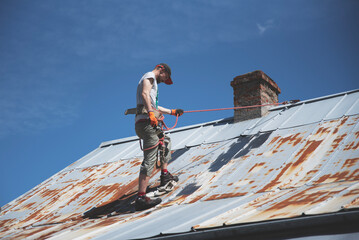 Mężczyzna malujący zardzewiały dach © Katarzyna